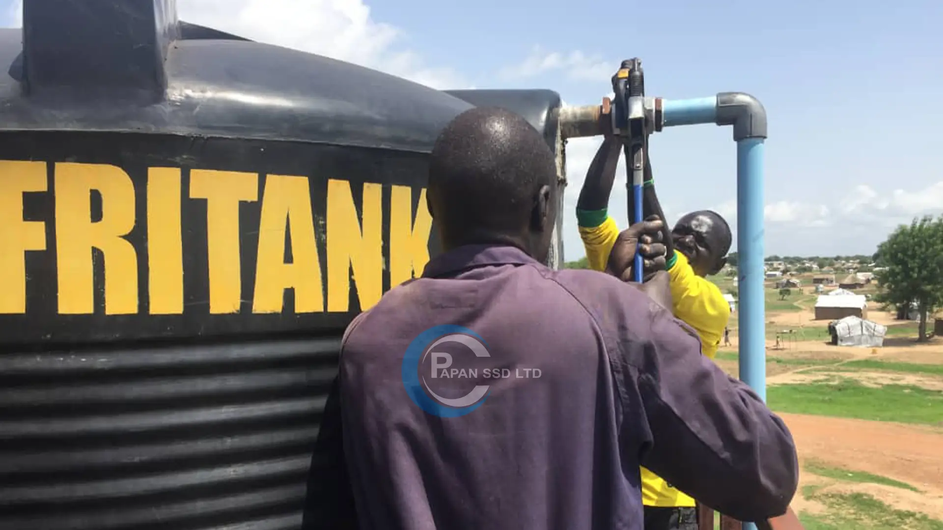 Technicians connecting the outlet pipe to an elevated water tank in Lakes State